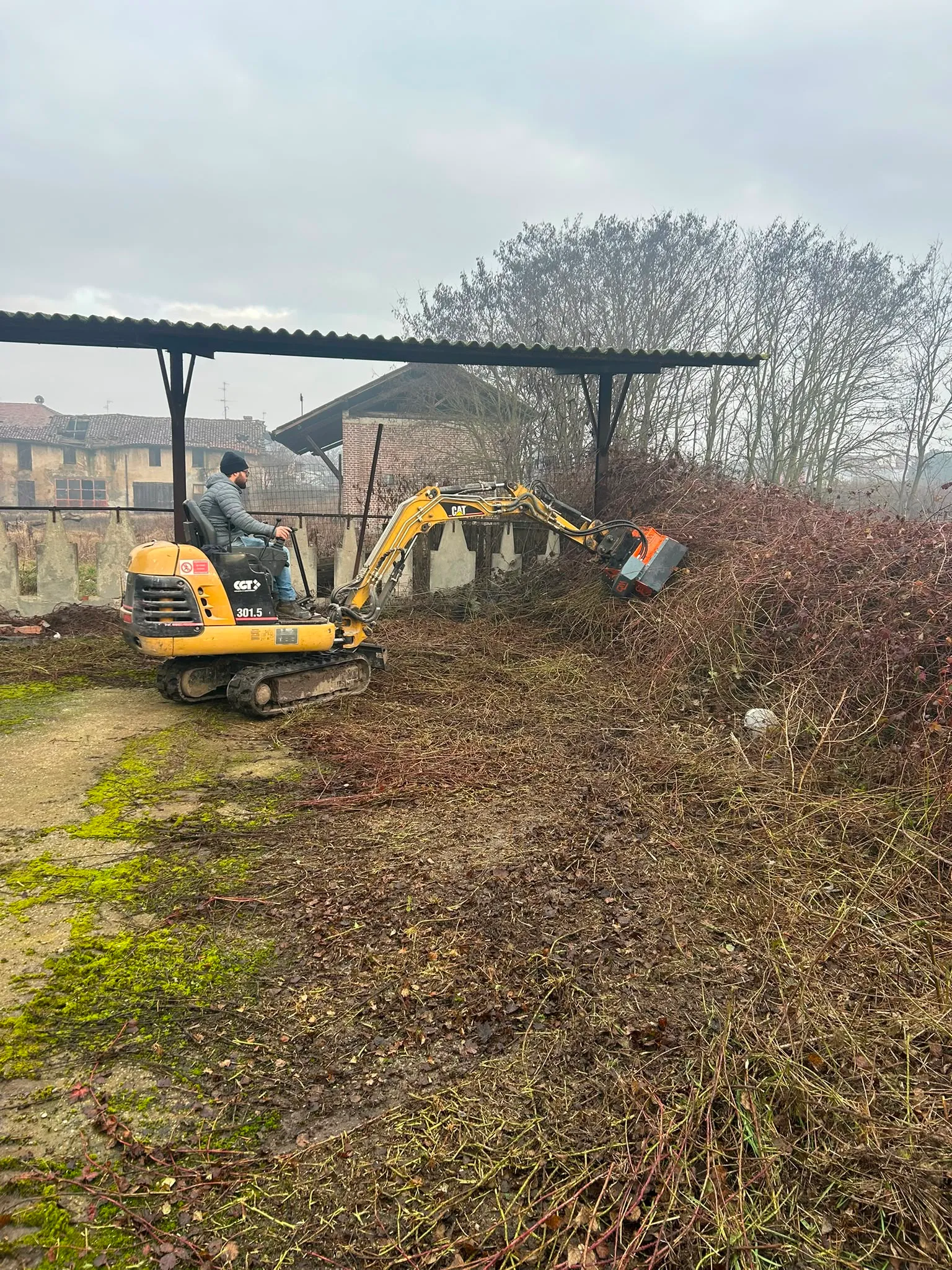 Sgombero di ramaglie con mini escavatore dopo manutenzione del verde